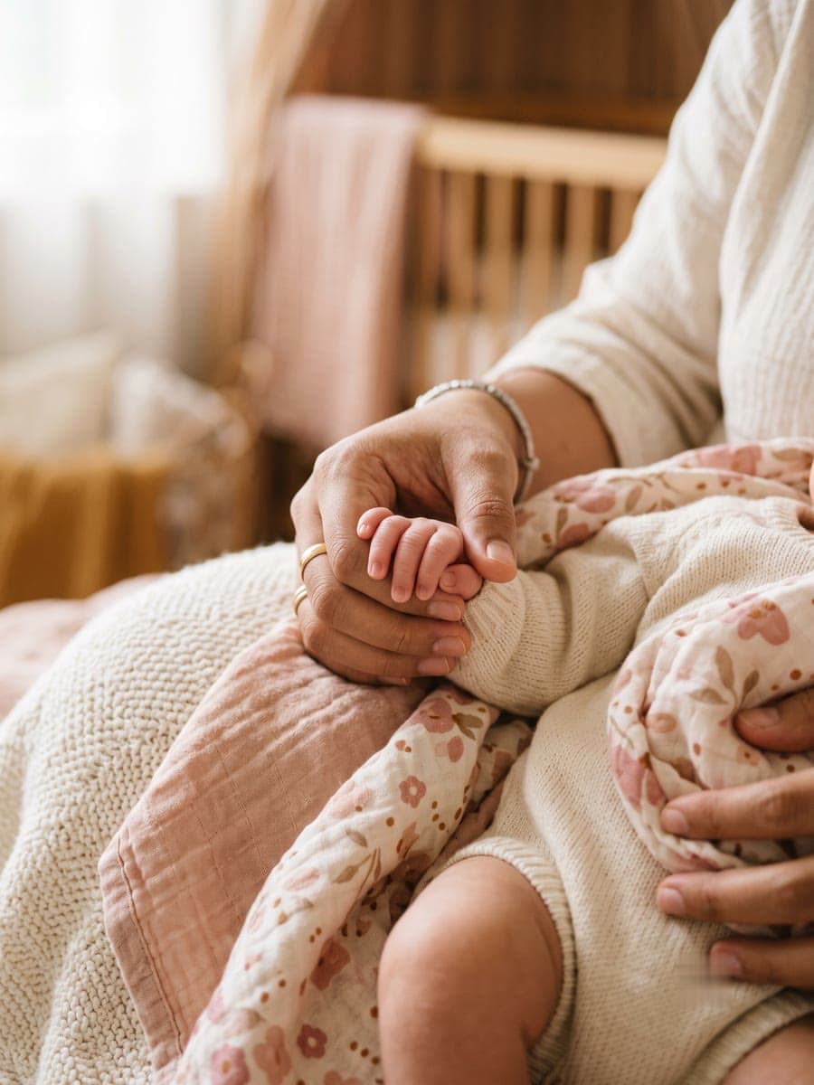 Tangan orang tua menggenggam tangan mungil bayi baru lahir di kamar bernuansa hangat